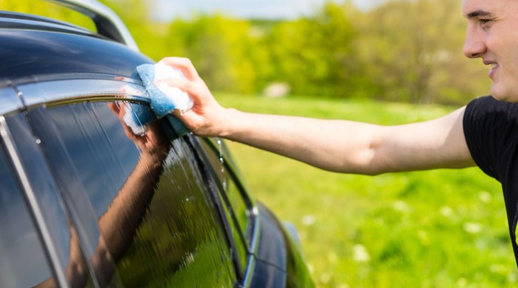 a man washing the windows of his black car from the outside
