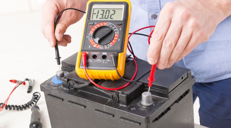 A car battery being tested with a multimeter