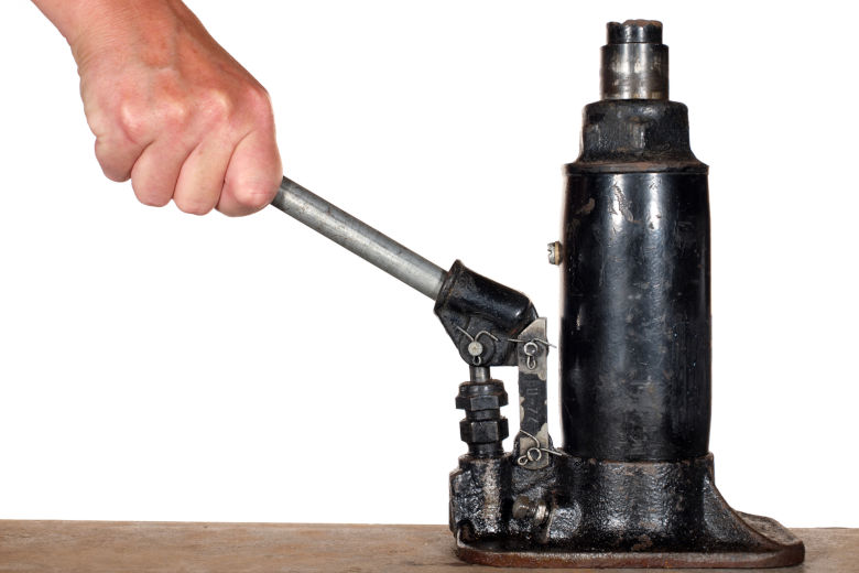 Mans hand pumping an hydraulic bottle jack isolated on white