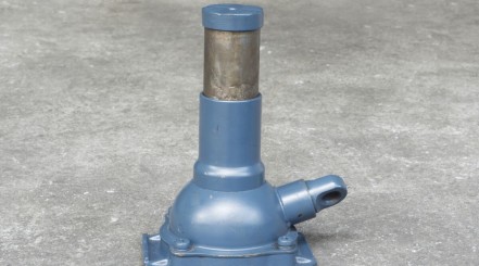 A blue hydraulic bottle jack on a concrete floor