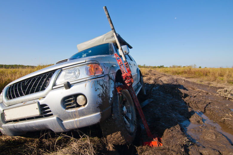 A hi lift jack lifting a 4x4 from deep mud