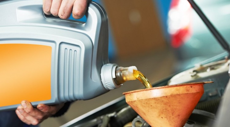 pouring oil into a car after figuring out how much it needs
