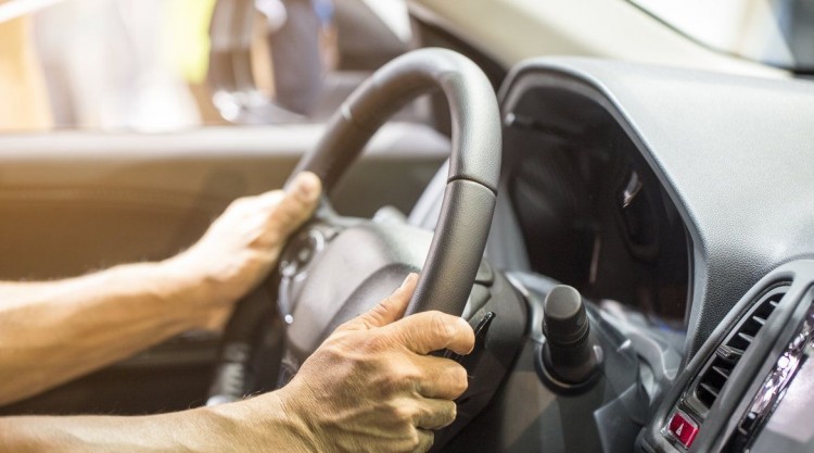 Man with two hands on the steering wheel trying to impose full control