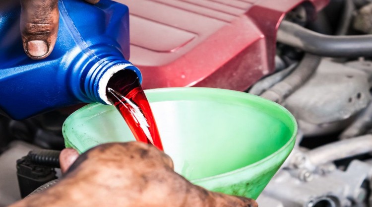 Man with dirty hands funneling transmission fluid into the car