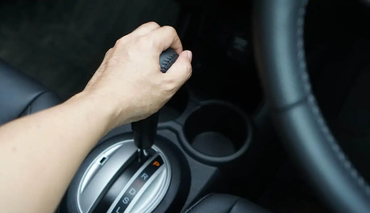 Drivers hand on a gear stick that is in park
