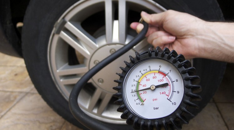 Close up of a pressure gauge in front of a car wheel, from a portable air pump for car tires