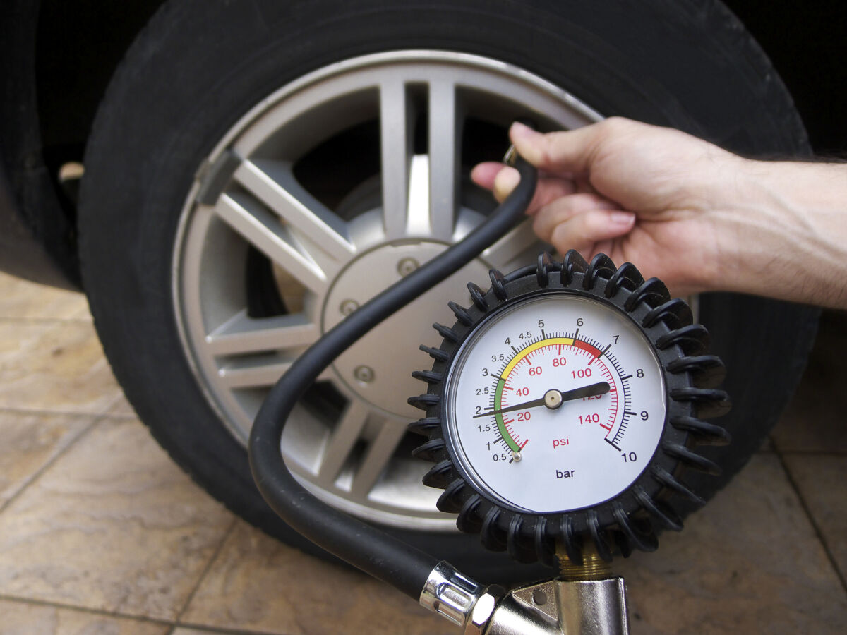 Close up of a pressure gauge in front of a car wheel, from a portable air pump for car tires