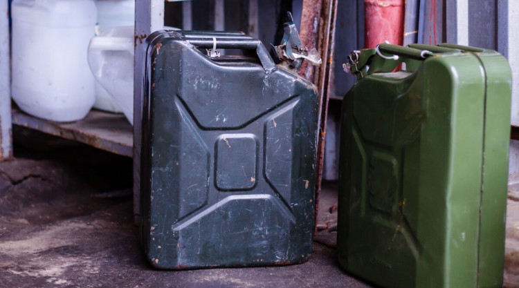 2 old fashioned military style jerry cans on a garage floor