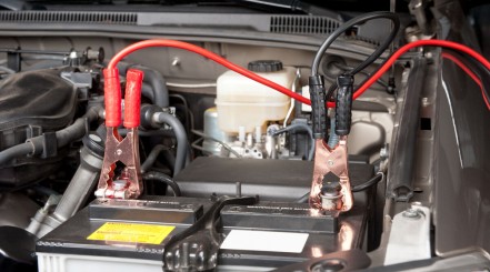 Battery maintainer cables transferring power to a battery still in the engine compartment