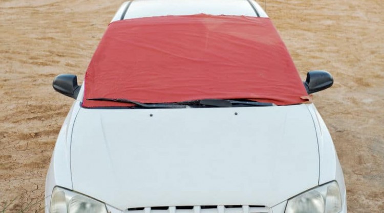 A white car with a red windshield cover