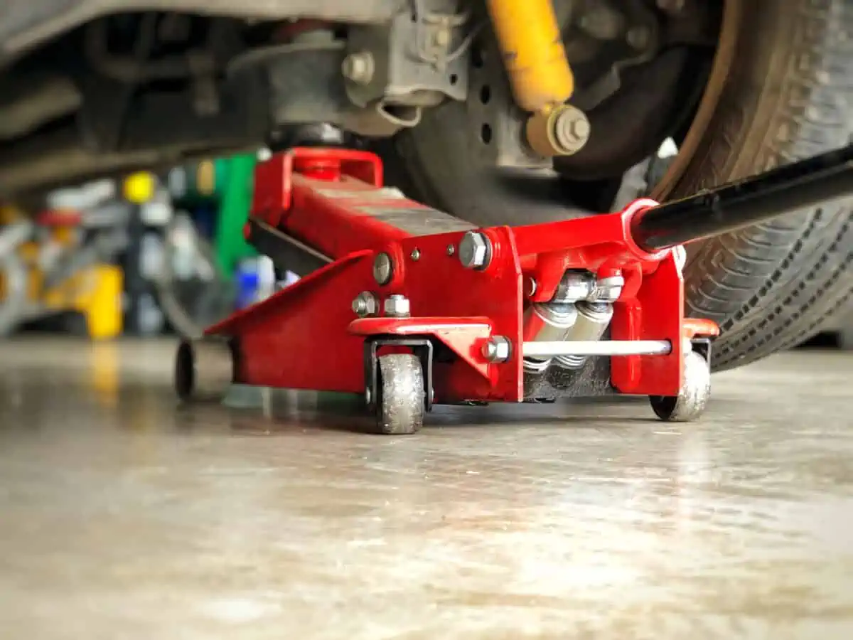 A red floor jack underneath a car