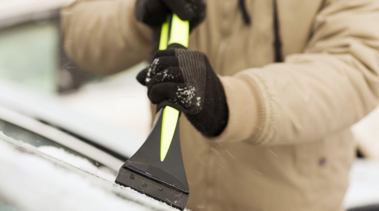 A man using an ice scraper on a car windscreen