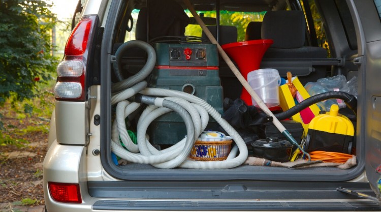 The trunk of an SUV fully and messily loaded with cleaning supplies