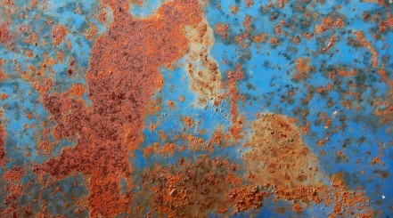 Close up of rust on a panel of a blue car