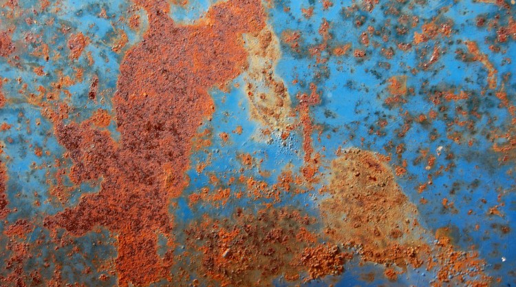 Close up of rust on a panel of a blue car