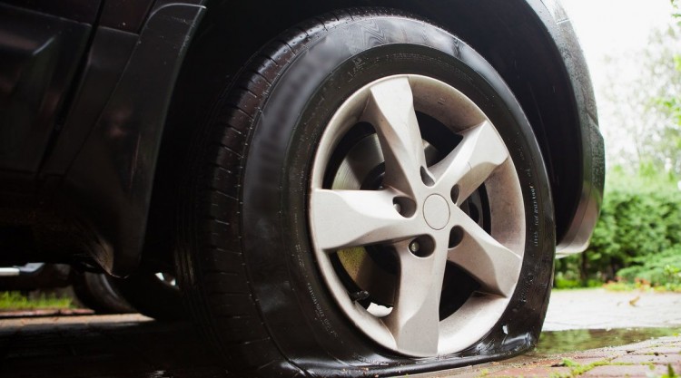 Black car parked at home with a flat tire that