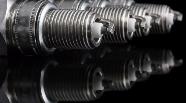 4 brand new spark plugs on a black background