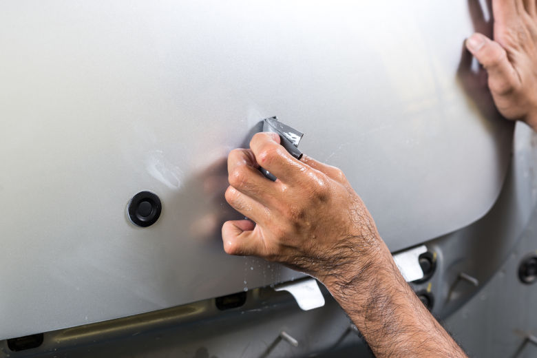 A man wet sanding part of a white cars bodywork