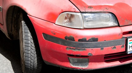 Red car with damaged exterior paint because of rust