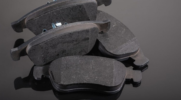 4 brake pads sitting on a shiny black surface