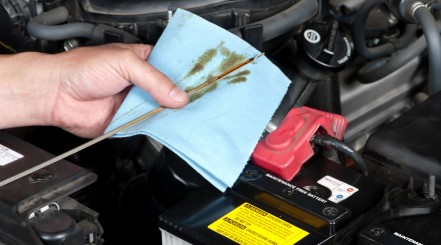 A mechanic checking engine oil levels, wiping off the dipstick