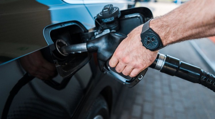 Man wearing black watch pumping his own gas in his black car