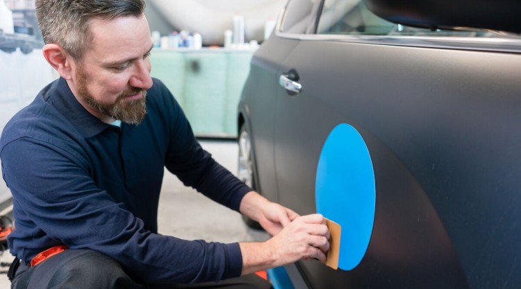 Mechanic working in a shop on a car sticker removal job