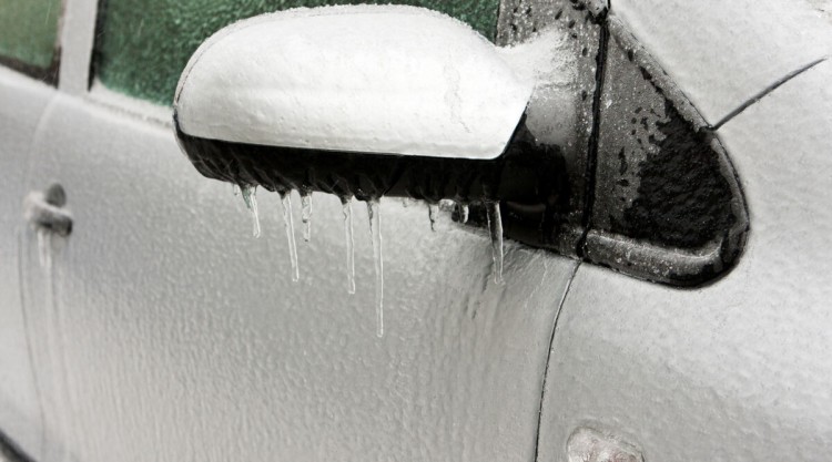 White car with frozen ice water on its exterior due to cold weather