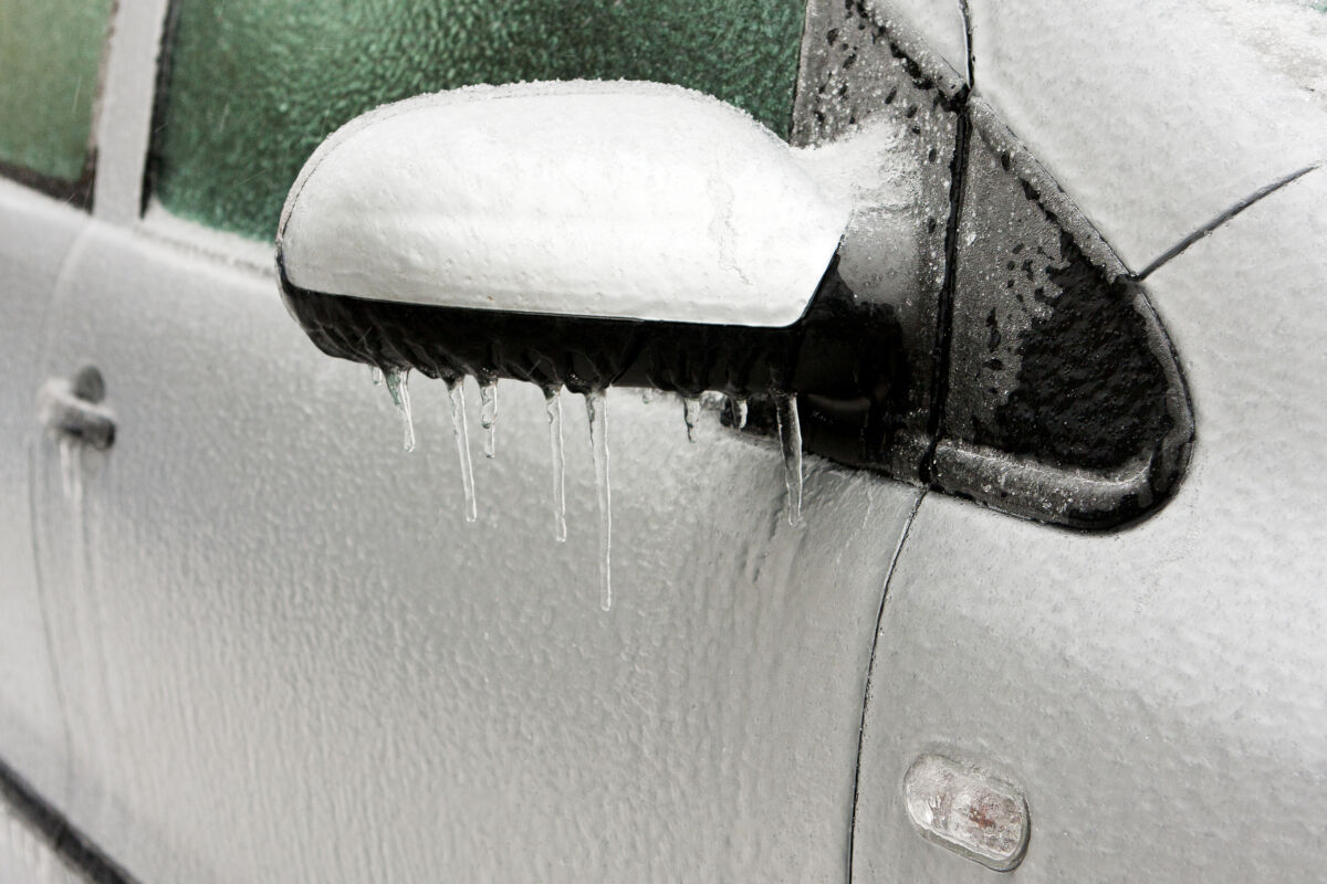 White car with frozen ice water on its exterior due to cold weather