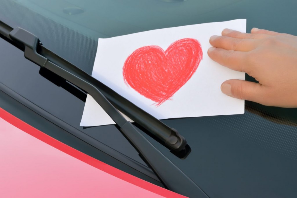 A love heart post it note being placed under wiper blades.