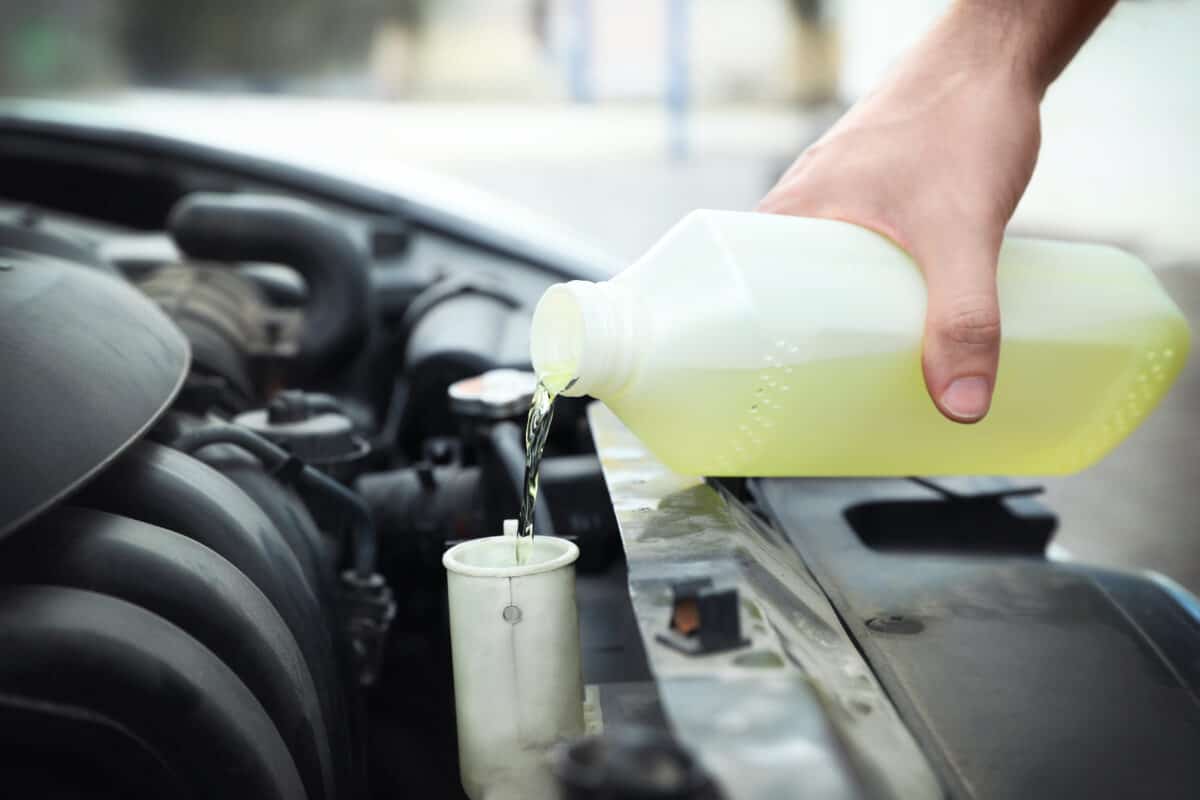 Yellow antifreeze being poured into a car engine