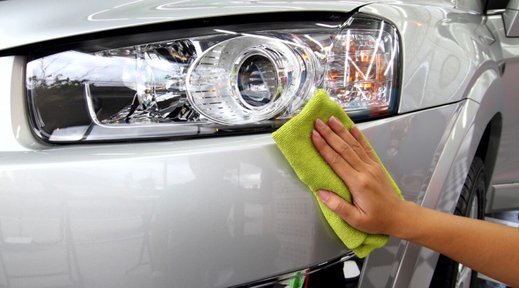 shining the headlights on a detailed silver car with a green cloth