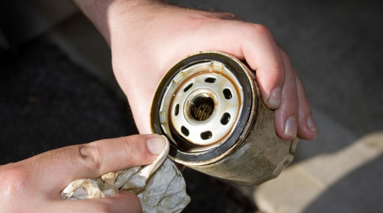 Close up of a removed and dirty oil filter in a mechanics hands