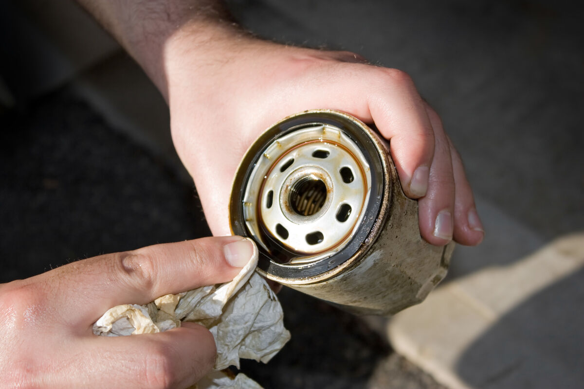 Close up of a removed and dirty oil filter in a mechanics hands