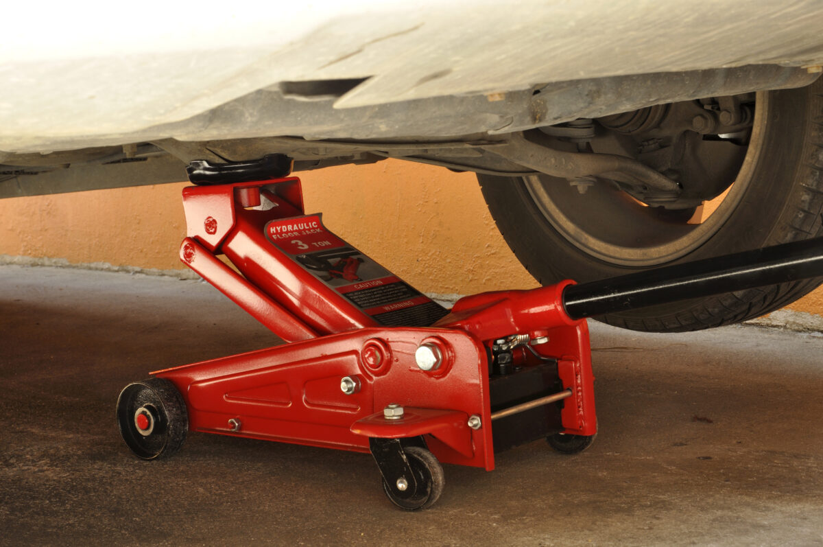 A red floor jack underneath a car