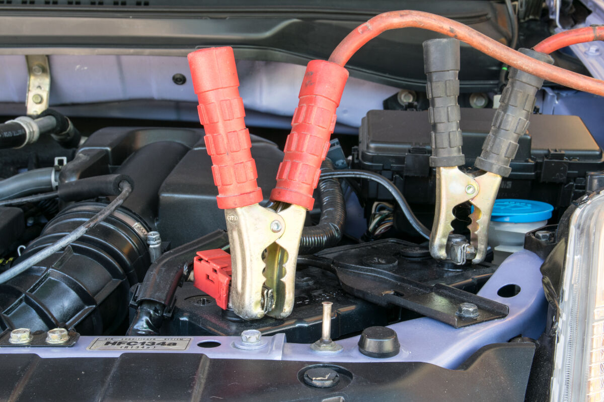 Car battery charger clamps connected to a battery inside a car engine compartment