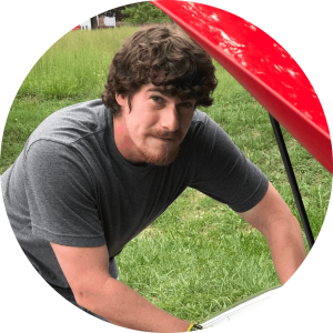 Shawn Furman, leaning into the engine of his red car, looking toward camera