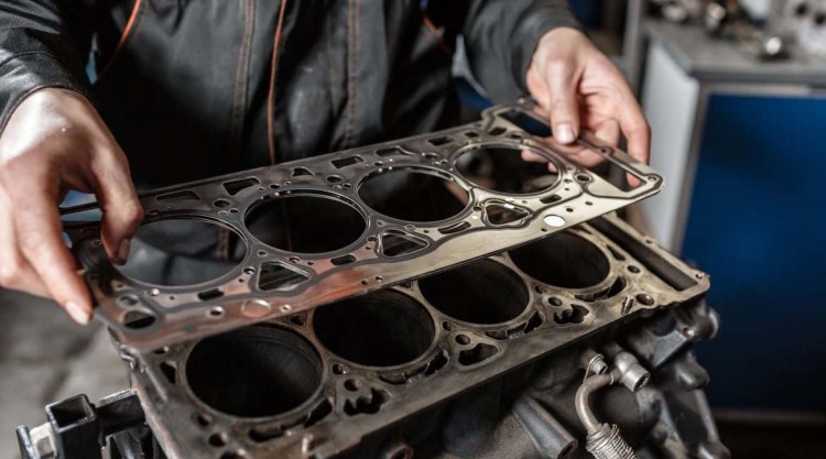 Mechanic holding a new head gasket to replace the blown head gasket