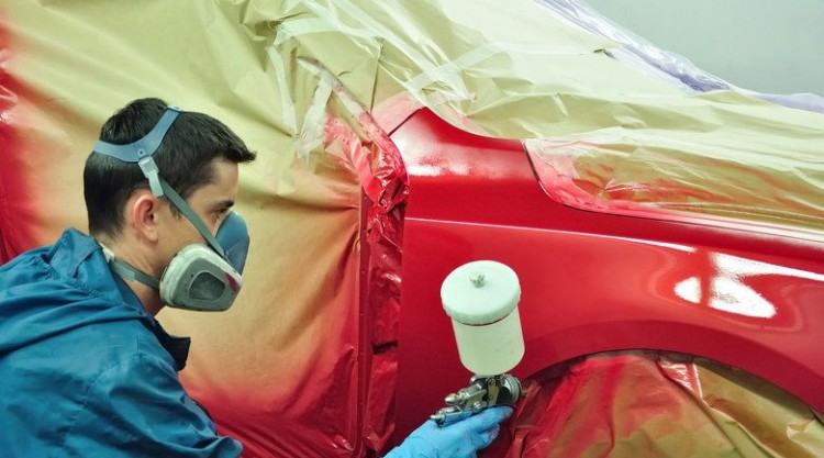 A man working on painting a red car