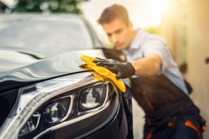 A man holding a microfiber cloth polishing a car after washing it