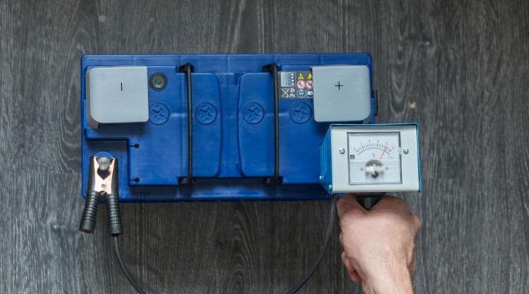 Analogue car battery tester being used to check a battery