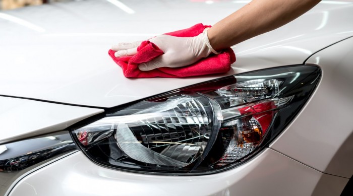 A white car being buffed with a red cloth