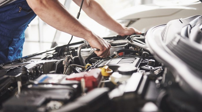 Car with hood open, and a mechanic performing some maintenance
