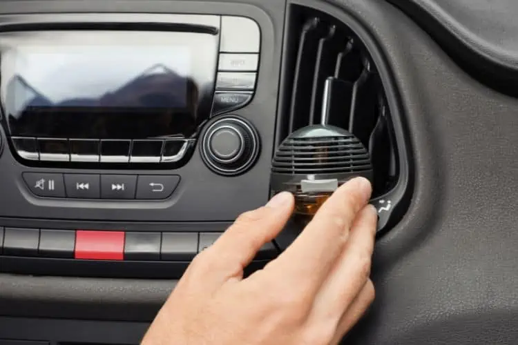 Man adjusting plug-in air freshener on dashboard air vent 