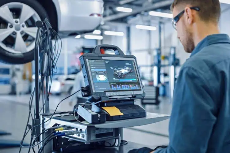 Mechanic running diagnostics software on a raised car