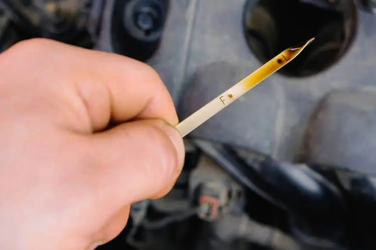 Person checking oil level in car engine