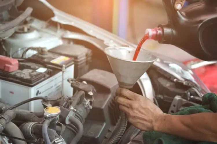 Person filling up car engine with transmission fluid