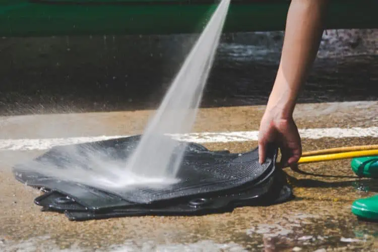 Pile of rubber car floor mats getting power washed