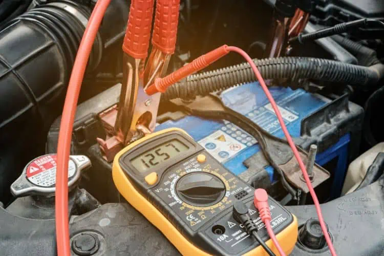 Using a multimeter connected to a car battery to measure the voltage