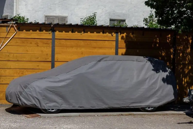 Car parked under tree with a car cover on